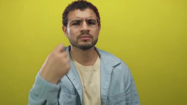 Adam sarı stüdyoda ciddi bakışlar ve görünürde jest ile elini işaret günlük gömlek giyerek; merak.