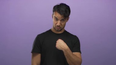 Siyah tişörtlü genç adam, parmak izole edilmiş mor arkaplan karşısında hayır işareti yapıyor. Onaylamıyor ve kendini dışa vuruyor.