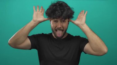 Sakallı genç İspanyol bir adam mavi bir arkaplan önünde neşe ve neşe ifade ediyor. Çeşitli jestler ve kendine güvenen bir gülümseme var..