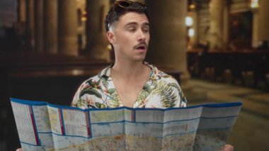 Çiçekli tişörtlü, elinde harita olan İspanyol genç adam, bir tatil gezisi sırasında turist olarak etrafı kolaçan ediyor..