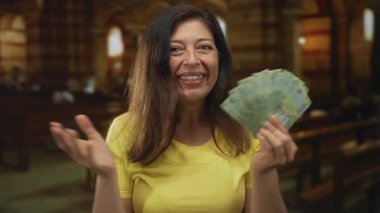 Orta yaşlı İspanyol kadın Şili pezosu banknotlarını klasik bir kilise nave içinde tutuyor; neşe cömertliği hayırseverlik umudu.