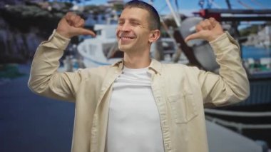 Güvenle gülümseyen bir adam deniz kıyısında kendini gösteren başparmaklarıyla görünür botlar, açık havada canlı, pozitif bir hava sergiliyor..