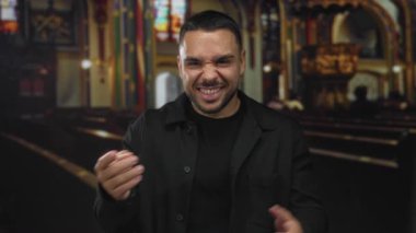 İnşaat koridorunda cam pencereli ve ahşap sıralı kamerayı işaret eden adam inancı karşılıyor.