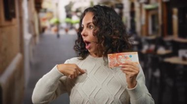 Kadın, açık hava restoranının terasında elinde Filipinli peso banknotuyla kahvede orta yaş sürprizini vurguluyor..