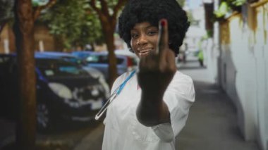 Mavi steteskoplu beyaz önlüklü kadın, kendinden emin ifadesiyle orta parmak gösteriyor..