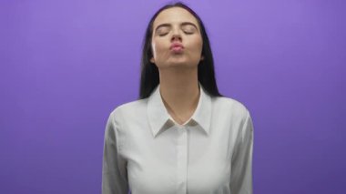 Beyaz gömlekli İspanyol kadın kalp hareketi yapıyor. Parmakları mor arka plan duvarına dayanıyor. Sevgi ve dostluk taşıyor..