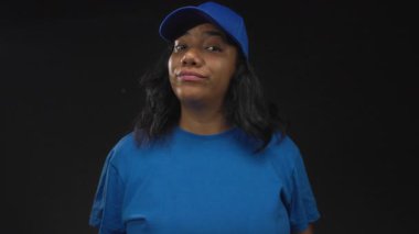 Stüdyoda mavi başlık ve ince gülümsemeli gömlek giyen ve kaşlarını kaldıran kadın elleri şakacı iğneleyici sözler sarf ediyor..