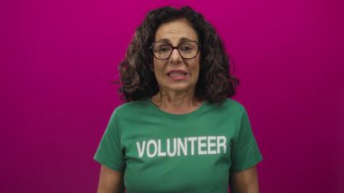 Orta yaşlı İspanyol kadın yeşil bir gönüllü tişört giyiyordu. Stüdyoda dişlerini buruşturuyordu. Mide bulantısı vardı..