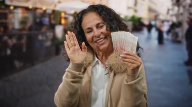Kalabalık bir caddede elinde Singapur dolarlarıyla gülümseyen ve kameraya el sallayan bir kadın..