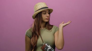 Pembe duvarın önünde kameralı şapka takan kadın İspanyol kökenli gezgin olarak düşünceli ve şık görünüyor.