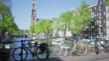 Yeşil ağaçlar ve tarihi binalarla dolu bir kanal boyunca bulanık bisikletler Hollanda 'nın kalbinde sakin, bulanık bir şehir manzarası yaratıyor..