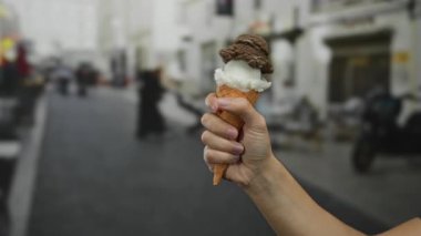 Şehir caddesinde elinde çikolatalı ve vanilyalı dondurma külahı tutan bir adam şehir yaşamını ve hoşgörüyü yakalıyor..