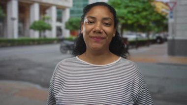 Gülümseyen kadın şehir caddesinde bulanık trafik geçmişi olan bir binayı işaret ediyor..