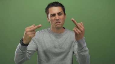 Genç ispanyol adam, yeşil duvardan önce stüdyoda çifte orta parmak hareketi sergiliyor..