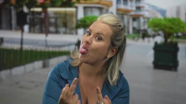 Sokak kaldırımında iki eliyle parmakla gösteren bir kadın. Mavi ceketli, gülümseyen bir kadın..