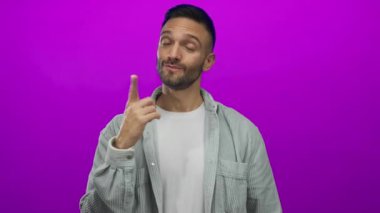 Kendine güveni olan İspanyol genç bir adam, parlak mor bir arka planı olduğunu, rahat bir gömlek giydiğini ve kendine güveni olduğunu söylüyor..