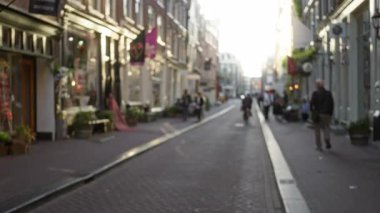 Bulanık insanlar klasik mimari, canlı vitrinler ve rahat bir şehir atmosferiyle büyüleyici bir Avrupa caddesi boyunca yürüyorlar..