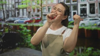 Gözleri kapalı gülümseyen ve caddeyi işaret eden bej tulumlu sarışın kadın. Mutluluk..