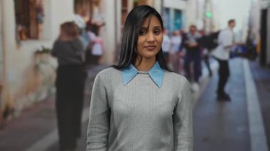 Sokakta el kol hareketi yapan ve kendini anlamlı bir şekilde gösteren genç bir kadın, çeşitli arka planda kalabalıkla canlı bir şehir ortamında duyguları yakalıyor..