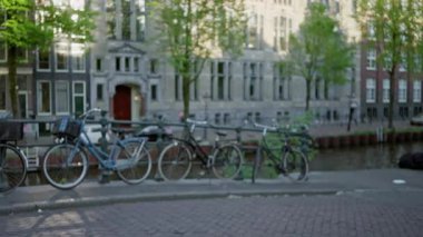 Bulanık tarihi binalar ve ağaçlar üzerine park edilmiş bisikletlerle sakin bir bokeh etkisi yaratıyor.