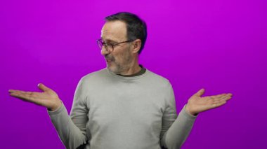 Avuç içlerini açık gösteren İspanyol bir adam canlı pembe bir duvara karşı izole edilmiş, merak ve sorgulama iletiyor..