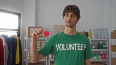 Bağış merkezinde insan kırmızı kalbi başparmağıyla işaret parmağı arasında tutar; merhamet derneği..