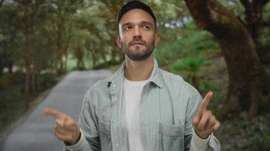 Serin yeşil bir parkta parmaklarıyla sayan genç İspanyol adam uzun ağaçların altında düşünceli bir dış mekan tasviri yapıyor..