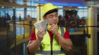 İnşaat işçisi, kasketli bir işçi, modern ofis ortamında bize kapalı yerlerde dolarları tutarken mali kararlarda belirsizlik gösteriyor..