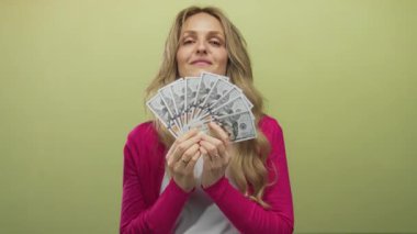 Amerika 'da heyecan ve zenginliği gösteren sarı bir arkaplan önünde dolar tutan genç bir kadın.