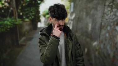 Şehir merkezindeki genç adam, şehir caddesinde dikkatli bir ifadeyle el kol hareketi yaparak açık bir çevrede tetikte olmayı ve farkındalığı öneriyor..