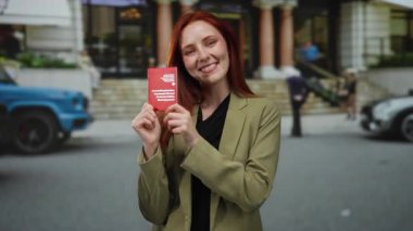 Elinde İsviçre pasaportu olan bir kadın şehrin caddesinde dikiliyor, kendine güvenen bir şekilde gülümsüyor..