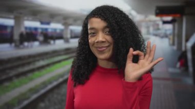 Kıvırcık saçlı Afrikalı Amerikalı kadın tren istasyonu inşaatında iyi bir jest gösteriyor..