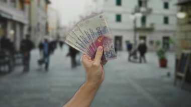 Arjantin pesolarını elinde tutan beyaz bir adam şehrin hareketli sokaklarında şehir içi yaşam arka planıyla ekonomik konsepti gözler önüne seriyor..