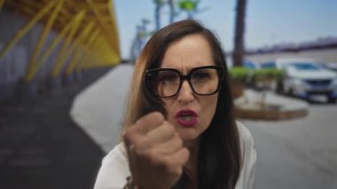 Sokakta kızgın bir şekilde bağıran kadın canlı şehir ortamında yumruğunu sıkmış yoğun duygular sergiliyor.