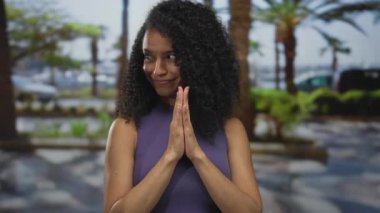 Kadın, arka planda palmiye ağaçları olan açık havada birlikte dua ediyor. Huzurlu bir şehir ortamı ve rahat bir atmosfer sergiliyor..