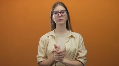 Stüdyoda el ele tutuşan gözlüklü genç sarışın kadın odaklanmış bakışlarla, sessiz bir yansıma..