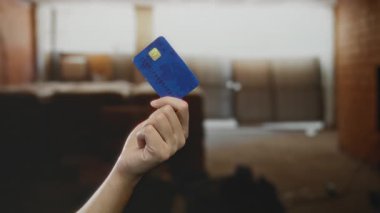 Ev yenileme ve geliştirme bağlamında yapılan mali işlemleri ve ödemeleri gösteren bir inşaat sahasında kredi kartı tutan beyaz bir adamın eli.
