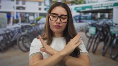 Yoğun caddedeki bisiklet kiralama istasyonunda gözlüklü genç İspanyol kadın kollarını kavuşturdu..