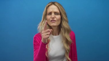 Duvarı işaret eden genç sarışın mavi arka planda cesur bir hareketle öfkesini vurguluyor..