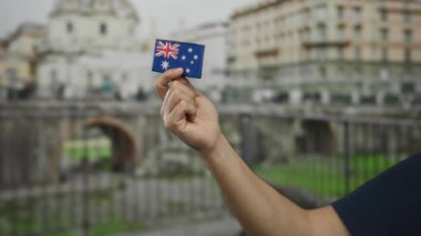 Roma harabeleri yakınlarında Avustralya bayrağı taşıyan bir adam, seyahat ve kültürel çeşitliliği ön plana çıkarıyor..