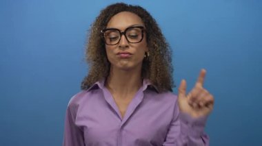 Mor bluz giyen İspanyol transseksüel kadın. Mavi stüdyoda el kaldırarak jest yapıyorum..