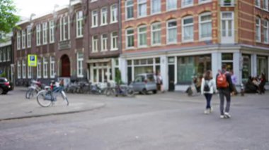 Amsterdam 'da klasik Avrupa mimarisine karşı bulanık insanlar ve bisikletli şehir manzarası, canlı bir sokak atmosferi yakalıyor.