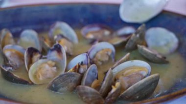 Akdeniz restoranındaki kapalı bir kasede, gümüş kaşıkla servis edilen gümüş soslu taze deniz ürünlerini sergileyen istiridyeler mutfak zarafetini ve sadeliğini ön plana çıkarıyor.