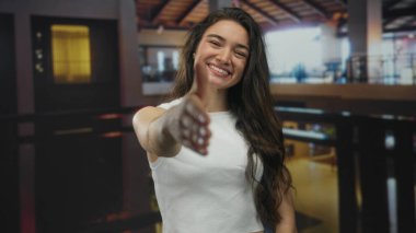 Kadın bina girişinde uzanmış el sıkışma ve geniş bir gülümseme sunuyor; dostça karşılama.