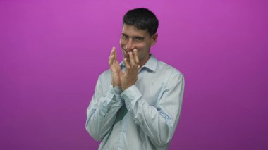 Açık mavi tişörtlü bir adam stüdyoda mor ışıkla aydınlatılmış sinsi bir gülümseme ile el sıkışır; beklenti.