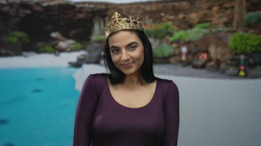 Bir havuz kenarında duran genç İspanyol kadın kayalık arka planda ve yemyeşil, açık havada zarafet ve gevşemeyi somutlaştıran bir tatil merkezinde..