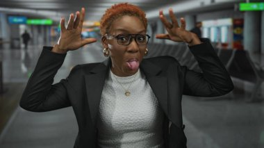 Genç Afrikalı Amerikalı kadın elini uzatıyor ve hareketli bir havaalanı terminalinde iki elini de kaldırıyor..