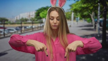 Şehir caddesinde tavşan kulağı takan bir kadın, şehir merkezindeki açık hava ortamında, hareketli ve kaprisli titreşimleri vurguluyor..