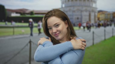 Sidikli kule binasında çıplak omuzlarını kucaklayan bir kadın, yavaşça gülümsüyor..