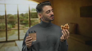 Adam waffle tadıyor ve kanepenin yanında kahve fincanı tutuyor..